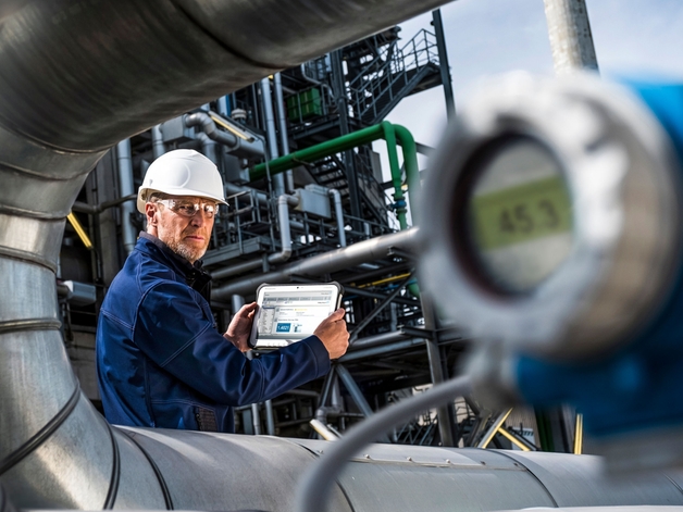 Ingeniero trabajando en una tablet industrial en una refinería.